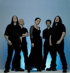 To-Mera -bändin viisi mustiin pukeutunutta hahmoa seisoo rivissä sinertävää taustakangasta vasten, jonka alaosasta hohtaa valoa. Keskimmäisenä seisoo mustaan mekkoon pukeutunut nainen, jonka hiukset kammattu taaksepäin.