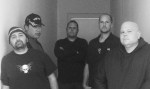 Mustavalkoinen ryhmäkuva Agenda Of Swine -yhtyeen viidestä miesjäsenestä, jotka seisovat valkoseinäisessä huoneessa, jonka takimmaisessa seinässä suljettu ovi.