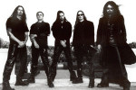 Mustavalkoinen ryhmäkuva Evergreyn miehistä, jotka seisovat valkoista taustaa vasten kivirappusilla. Miehiä kuvassa viisi kappaletta. Heillä mustat vaatteet, osalla myös mustat pitkät hiukset.
