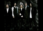 Tummasävyinen ryhmäkuva My Dying Bride -bändin miehistöstä, joka on pukeutunut mustiin vanhan ajan pukuihin. Heillä on kullakin valkoiset aluspaidat päällysvaatteidensa alla. Miehet seisovat rivissä tummaa taustaa vasten. Heitä kuvassa viisi kappaletta.
