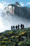 Entwine-bändin miehistö seisoo kirkkaan taivaan alla ja suuren jyrkän pilvien ympäröimän vuoren edustalla vihreällä niityllä. Kuvassa näkyy kaukaisuudessa Entwinen jäsenet, jotka seisovat rivissä osittain udun peittäminä.