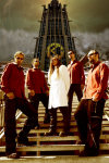 Courageous-bändin promokuva vuodelta 2006. Miehistö seisoo suuren pilvenpiirtäjän edustalla portailla. Heitä kuvassa viisi kappaletta. Keskimmäisellä pitkät hiukset ja pitkä valkoinen lääkärintakki yllään, muut miehet seisovat hänen vierillään punaisiin p