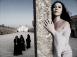 Ava Inferin promootiokäyttöön tarkoitettu valokuva, jossa oikeassa laidassa valkoisiin pukeutunut mustahiuksinen nainen nojailee kulmikasta betonipaalua vasten. Naisen takana, vasemmalla, kolme mustanpuhuvaa munkkikaapuihin sonnustautunutta ihmistä. He ov