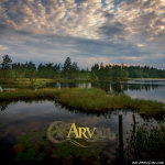 Ásmegin-nimisen norjalaisbändin "Arv"-albumin kansikuva. Kuvassa valokuva kauniista luontomaisemasta, jossa tyyntä merta ja sen seassa vihreitä saarelmia ja niittyjä, puustoa ja kaunis pilvinen taivas. Albumin logo kuvan alaosassa keskitettynä kellertäväl