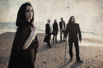 Theatres des Vampiresin joukot seisovat ulkoilmassa pukeutuneina mustiin vaatteisiin. Kuvassa etualalla mustahiuksinen nainen, jonka takana hietikolla merenrannalla seisoo neljä mustiin pukeutunutta miestä.