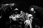 Harmaasävyinen valokuva Finntrollin jäsenistä, jotka seisovat mustaa taustaa vasten mustat tai tummanharmaat vaatteet yllään. Kuvan jäsenet ovat miehiä. Jokaisella heistä pitkät hiukset, osalla myös corpsemaskit kasvoilla.