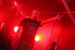 Rotten Soundin jäsen punaisten valojen sävyttämässä valokuvassa musta t-paita yllään ja vasen käsi ojossa. Miehellä kalju pää.