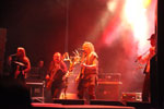 Valokuva esiintymislavalla soittavasta Korpiklaani-yhtyeen kokoonpanosta. Kuvan muusikot seisovat spottivalojen loisteessa punertavassa valaistuksessa.