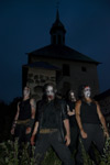 Synkkä ryhmäkuva neljästä pitkäletistä, jotka ovat mustiin pukeutuneita miehiä ja joiden kasvoilla corpsemaskit. Kuvassa taustalla kirkko hämärtyvää yötaivasta vasten.