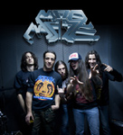 Madmaze-bändistä otettu ryhmäkuva, jossa näkyy viisi muusikkoa tummansinistä seinää vasten.