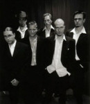 Mustavalkoinen valokuva Fall of the Leafe -ryhmän jäsenistä, joita kuvassa näkyy kuusi kappaletta. Miehet pukeutuneet mustiin pukuihin. Puvussa valkoinen paita ja musta päällystakki.