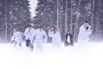 Ryhmäkuva Embassy of Silencen kokoonpanosta tarpomassa lumihangessa kuusimetsän edustalla.
