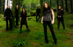Norjalaisen Octavia Sperati -bändin jäsenet seisovat vihreän metsän siimeksessä. Kuvassa kuusi hahmoa, joista osa on naisia. Kaikilla yllään mustat vaatteet.