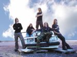 Amoral-yhtyeen viisi jäsentä seisoo ränsistyneen valkoisen Volvon ympärillä. Osa miehistä seisoo auton konepellillä ja katolla. Taivas on sininen ja pilvinen.