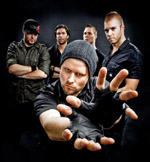 Ryhmäkuva Machinae Supremacy -bändin jäsenistä. Kuvassa viisi miestä, joitka seisovat mustaa taustaa vasten.