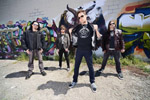 Newsted-bändin kokoonpanossa neljä miestä. He seisovat graffitein koristeltua seinää vasten ulkoilmassa.