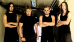 Pitchblack-bändin neljä miestä seisoo rivissä matalakattoisen huoneen suuaukon edessä. Heistä jokaisella mustat vaatteet yllään. Kolmella neljästä hihattomat paidat, neljännellä t-paita.