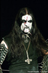Gorgoroth-bändin jäsen seisoo mustaa taustaa vasten sonnustautuneena tyypillisin black metal -miehen varustein. Naama mutrussa, corpse-maskit poskilla, hiukset musta ja ylösalaisin käännetty risti kaulassa.