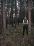 Bladesmith-sooloprojektin Erik Wray seisoo keskellä mäntykorpea. Miehellä oliivinvärinen hihaton paita ja mustat housut. Hänellä pitkät hiukset.