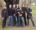 Ivory Moon -bändin seitsemänhenkinen kokoonpano, johon kuuluu kuuden miehen lisäksi yksi napapaitaan pukeutunut nainen, seisoo keskellä nurmikkoa suurehkoa puuta vasten.