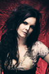 Anette Olzon, eli Nightwishin laulaja, poseeraa tummanpunaista taustaa vasten pukeutuneena valkoiseen lyhythihaiseen paitaan. Naisella pitkät mustat hiukset, kasvoilla tyyni ilme.