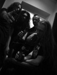 Sävyltään tumma ja värimaailmaltaan mustavalkoinen promokuva Necrodeath-yhtyeen kokoonpanosta, johon kuuluu neljä miestä. Heistä kolmella pitkät hiukset, neljännellä musta irokeesi.