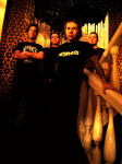 Deathbound-bändin jäsenet ryhmäkuvassa, joka on värimaailmaltaan kellertävä ja lämmin. Miehet seisovat rykelmänä portaiden yläpäässä pukeutuneena mustiin vaatteisiin, kahdella etummaisella yllään bändipaidat.