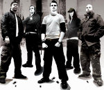 Harmaasävyinen bändipotretti Born From Pain -nimisen ryhmän viidestä miehestä, jotka seisovat rivissä ylivalottuneessa kuvassa. Miehet pukeutuneet pääsääntöisesti tummiin vaatteisiin, arkivaatteisiin.