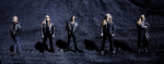 Tummansininen valokuva Tarotin jengistä, johon kuuluu viisi miestä. He seisovat rivissä soran seassa. Miehillä pitkät vaaleat hiukset, nahkatakit ja mustat housut.
