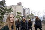 Opeth-yhtyeen promokuva, jossa bändin jäsenet seisovat ulkoilmassa suuren betonirakennuksen edustalla. Rakennus saattaa olla viljasiilo. Etummaisena vasemmassa laidassa seisova mies, jolla pitkät vaaleanruskeat hiukset ja viiksi-parta –yhdistelmä.