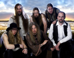 Kuusi Korpiklaani-nimisen folk metallia soittavan yhtyeen jäsentä seisoo ja istuu auringonlaskun tai –nousun edessä.