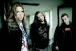 Kolme Apocalyptica-yhtyeen sellistiä, jotka ovat miehiä, seisovat valkoiseksi maalatussa huoneessa. Kahdella vasemmanpuoleisella hepulla pitkät hiukset, oikeanpuoleisella lyhyt musta tukka.